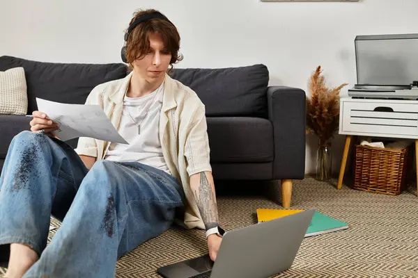 Genç bir öğrenci evde ders çalışır, not alırken bir dizüstü bilgisayar kullanır..