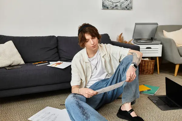 Odaklanmış genç bir öğrenci rahat bir ev ortamında otururken notlarını gözden geçirir..