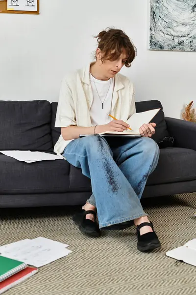 Genç bir adam, notlar ve kitaplarla çevrili, evde çalışır ve yazar..