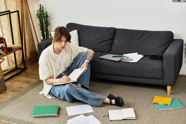 Odaklanmış genç adam, rahat bir yerde ders çalışırken yere oturup notlar yazıyor.