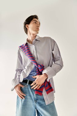 İkili olmayan genç bir kişi modern uzayda kendine güvenen şık bir kıyafet sergiliyor..