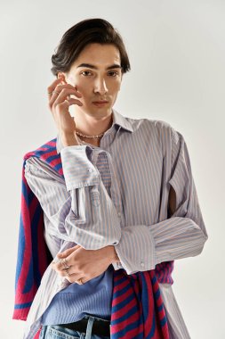 Şık, ikili olmayan bir birey, canlı bir kıyafet ve aksesuar sergileyerek kendine güvenerek poz verir..