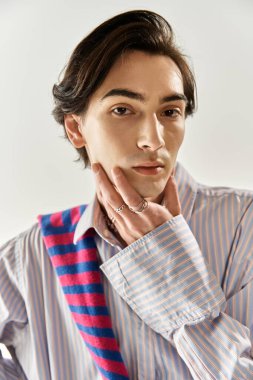 Tarz sahibi, genç, ikiliden olmayan bir kişi kimliğini belli ederken kendine güvenir bir şekilde poz verir..