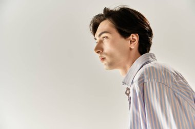 İkili oynamayan genç bir insan şık kıyafetlerini ve özgüvenini minimalist bir ortamda sergiliyor..