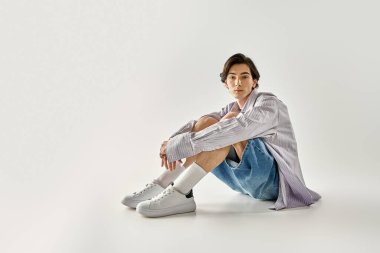 Kendine güveni olmayan kişi, canlı bir stil sergileyen minimalist bir stüdyoda poz verir..