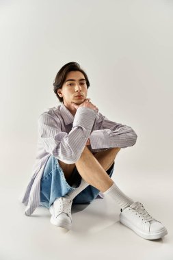 İkili olmayan bir birey zarif bir şekilde yerde oturuyor, modern moda ve güveni sergiliyor..