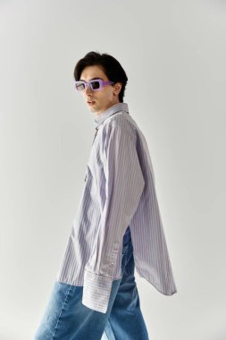 Şık, genç, ikili olmayan kişi, basit bir arkaplana karşı canlı kıyafete olan güvenini gösteriyor.