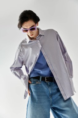 İkili olmayan şık kişi kendine güvenerek duruyor, modaya uygun kıyafetler ve aksesuarlar sergiliyor..