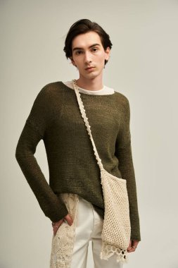 İkili olmayan genç bir insan şık bir kıyafet içinde, kendine güven ve yaratıcılık yayarak poz verir..