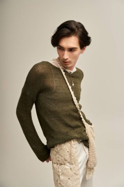 Genç, modaya uygun olmayan bir kişi kendine güvenen, şık bir elbiseyle poz verir..