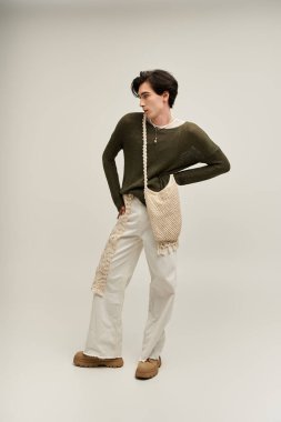 İkili olmayan şık bir şahıs, gururlu ve moda dolu bir sanat stüdyosunda kendine güvenerek poz verir..