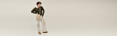 İkili olmayan genç bir kişi, minimalist bir alanda benzersiz bir moda sergiliyor, kimliğini ve afişini ifade ediyor.
