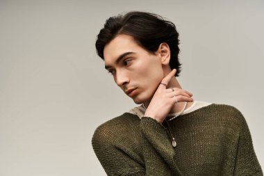 Şık, genç, ikili olmayan bir birey kendine güvenen, gururlu ve kendini beğenmiş bir şekilde poz verir..