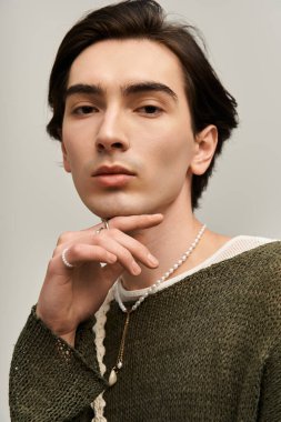 Genç, ikili olmayan kişi kendine güveni olan şık kıyafetler ve stüdyoda düşünceli pozlar veriyor..