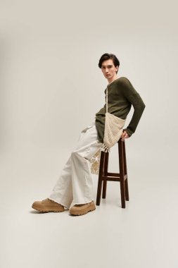 İkili olmayan genç bir insan, benzersiz modasını minimalist bir stüdyo ortamında sergiliyor..