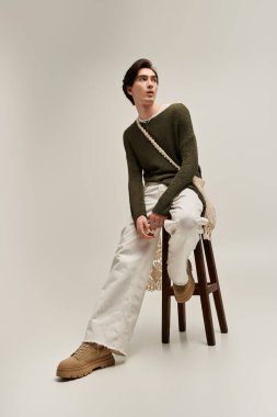 Genç ikili olmayan kişi, kapalı mekan ortamında modern moda sergiliyor.