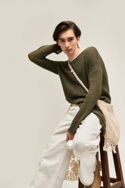 İkili olmayan genç bir insan moda anlayışını sakin bir stüdyoda özgüven ve duruş ile sergiliyor..