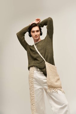 Şık, genç, ikili olmayan bir kişi moda anlayışını kapalı mekanda sergiliyor..