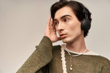 İkili olmayan şık bir kişi kulaklıklarını ayarlarken eşsiz modasını sergiliyor..