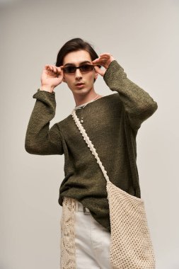 Şık, genç, ikili olmayan bir birey, canlı bir kişisel kimlik sergileyerek kendinden emin bir şekilde poz verir..