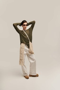 İkili olmayan şık bir birey minimalist bir stüdyoda kendine güvenerek duruyor..