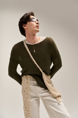 İkili olmayan şık bir genç, minimalist bir stüdyoda eşsiz bir moda sergiliyor..