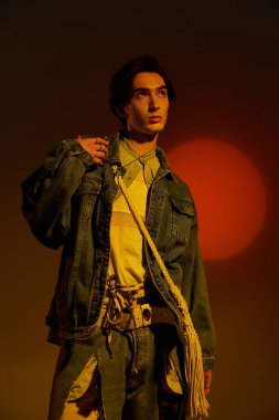 Şık, genç, ikili olmayan bir birey, canlı bir günbatımı altında moda anlayışını sergiliyor..