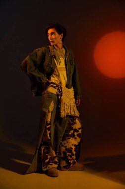 Genç, şık olmayan bir kişi zengin renklerle çevrili eşsiz moda anlayışını sergiliyor..