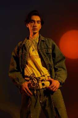 Genç, modaya uygun olmayan bir kişi altın saat boyunca şık bir kot giysisi giyer..