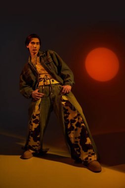 Şık, genç, ikili olmayan bir kişi, gün batımında cesur bir moda ifadesi sergiliyor..