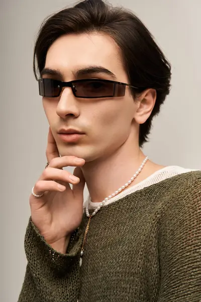 Genç, ikili olmayan bir birey, modaya uygun kıyafetlerini ve aksesuarlarını vurgulayarak kendine güvenerek poz veriyor..