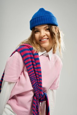 Güzel, genç bir kadın, kendine güvenen, mavi bereli, renkli bir elbiseyle şık bir şekilde gülümsüyor..