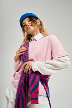 Kendine güvenen genç bir kadın şık bir elbise ve mavi bir bereyle parıldıyor, canlı bir cazibe yayıyor..