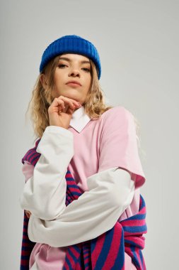 Güzel genç bir kadın modern bir stüdyoda mavi bir bereyle şık bir elbiseyle poz veriyor..