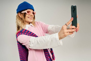 Genç bir kadın şık bir elbise içinde mavi bereli bir selfie çekiyor..