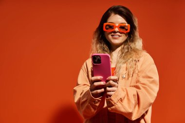 Güzel, genç bir kadın şık bir kıyafet giyerken telefonuna neşe içinde bakar..