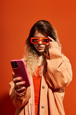 Şık giyinmiş güzel genç bir kadın telefonuyla bağlantı kuruyor, enerji saçıyor..