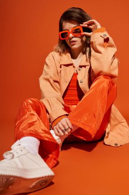 Genç kadın modaya uygun turuncu elbisesini sergiliyor, kendine güvenini ve tarzını sergiliyor..