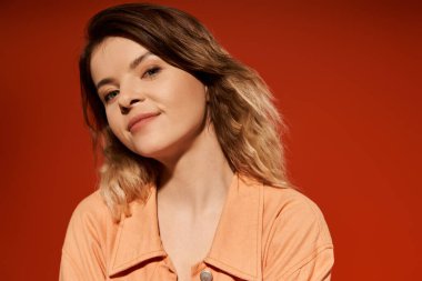 Kendine güvenen genç bir kadın moda anlayışını canlı turuncu elbisesiyle sergiliyor..