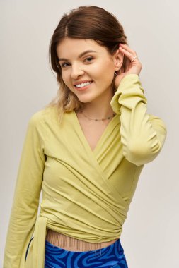 Güzel, genç bir kadın şık bir elbiseyle rahatça poz verir. Havalı bir tarzı ve neşesi vardır..