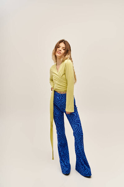 A beautiful young woman exhibits a trendy outfit featuring vibrant blue pants and a chic top.
