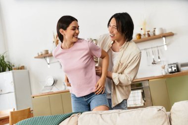 Çift evde şakacı etkileşim içinde, gülümsüyor ve samimi bir şekilde eğleniyor..