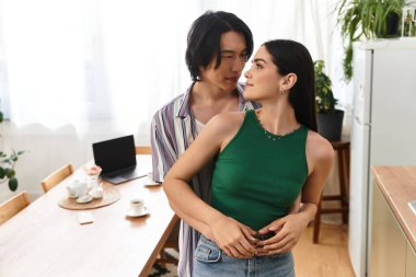 Bir erkek ve kadın, kişisel dokunuşlarla dolu sıcak bir evde sevgiyle kucaklaşırlar..