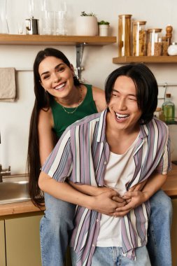 Mutlu bir çift, birbirlerine eşlik etmekten zevk alır. Davetkar mutfaklarında gülüp kucaklaşırlar..