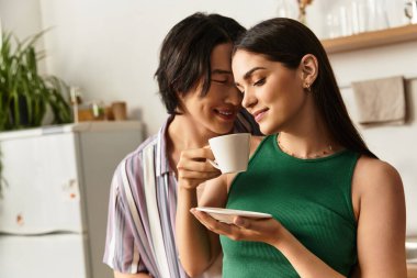 Neşeli bir çift evde hassas bir anın tadını çıkarıyor, kahveyi paylaşıyor ve sıcaklıkla gülümsüyor..