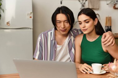 Sevgi dolu çift birbirine yakın oturur, bilgisayarlarını paylaşır ve mutfaklarında kahvelerini yudumlarlar..