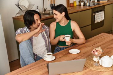 Çift ahşap bir masada oturuyor, kahkahalarını ve sıcak içkilerini paylaşıyorlar..