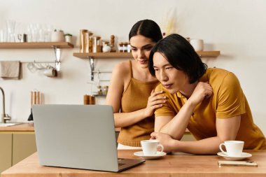 Çift, rahat mutfak masalarında dizüstü bilgisayarla uğraşırken sıcak bir bağı paylaşıyor..