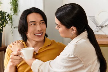 İki insan bir kahve fincanı tutarken birbirlerine gülümseyerek ve sıcaklıkla gülümserler..