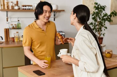 Bir erkek ve bir kadın sıcak bir mutfakta tatlı ve içeceklerle sıcacık bir kahvaltı yaparlar..